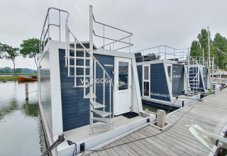 Moderne woonboten met dakterras aangemeerd bij Marina Parcs Amsterdam, Nederland, langs een houten steiger.