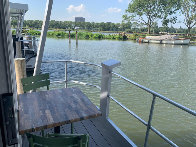 View from houseboat Harbour Lodge Amsterdam at Marina Parcs with table and chairs overlooking water.