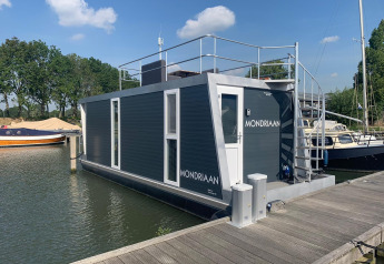Een moderne woonboot genaamd Mondriaan aangemeerd bij Marina Parcs Amsterdam in Nederland op een zonnige dag.