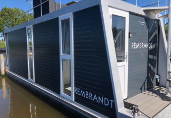 Moderne husbåd med navnet Rembrandt ved Marina Parcs Amsterdam, fortøjet på kanalen i Holland.