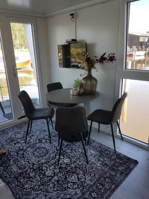 Comedor en casa flotante Harbour Lodge Amsterdam en Marina Parcs, mesa redonda, sillas modernas, vistas.