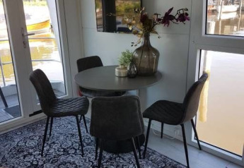 Comedor en casa flotante Harbour Lodge Amsterdam en Marina Parcs, mesa redonda, sillas modernas, vistas.