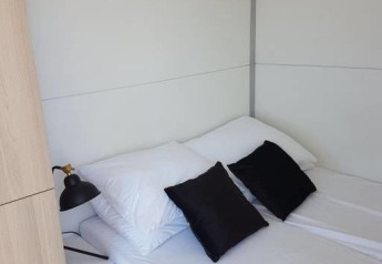 Dormitorio luminoso en una casa flotante con cojines blanco y negro y arte de aves en la pared en Ámsterdam.