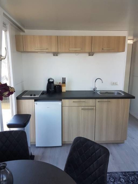 Moderne kitchenette op een woonboot bij Harbour Lodge Amsterdam, met houten kasten en compacte toestellen.