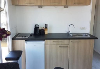 Moderne kitchenette op een woonboot bij Harbour Lodge Amsterdam, met houten kasten en compacte toestellen.
