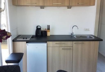 Moderne keukenhoek op een woonboot bij Harbour Lodge Amsterdam, met houten kasten en compacte apparatuur.