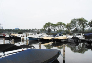 Woonboten bij Harbour Lodge Amsterdam in Marina Parcs Amsterdam, met bomen zichtbaar op de achtergrond.