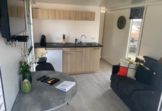 Interior moderno de casa flotante en Harbour Lodge Amsterdam con cocina, mesa y sofá en Marina Parcs, Países Bajos.