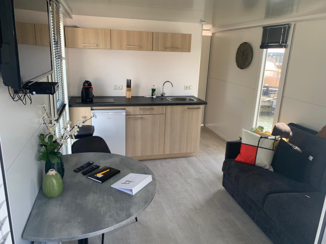 Intérieur moderne de péniche au Harbour Lodge Amsterdam avec cuisine, table et canapé à Marina Parcs, Pays-Bas.