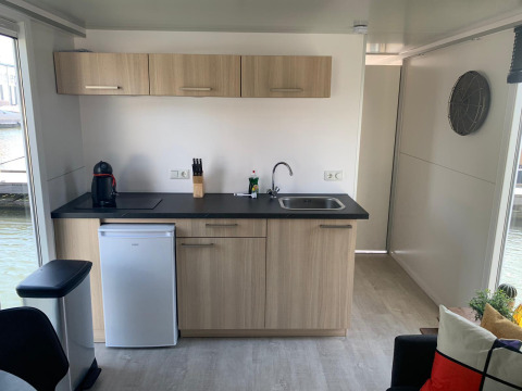 Moderne keuken op woonboot bij Marina Parcs Amsterdam met houten kasten, spoelbak en mini-koelkast.