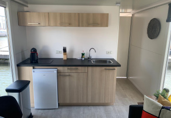 Cocina moderna en casa flotante con armarios de madera, fregadero, nevera y cafetera en Marina Parcs.