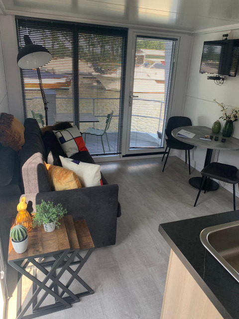 Sala de estar en una casa flotante en Harbour Lodge Amsterdam con decoración moderna y vistas a la marina.