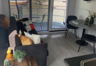 Salon d'une péniche au Harbour Lodge Amsterdam, décor moderne et vue sur la marina à travers les fenêtres.