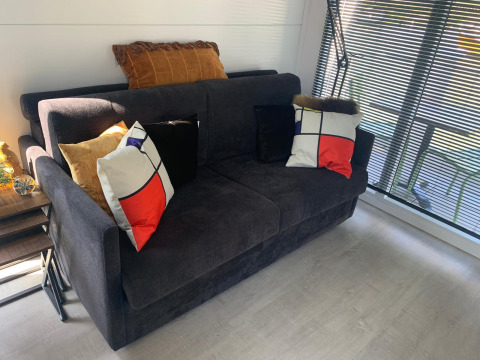 Moderne leefruimte op woonboot Harbour Lodge Amsterdam met zetel, kussens en grote ramen.