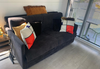 Modern living area on houseboat Harbour Lodge Amsterdam featuring comfy sofa, designer pillows, and windows.