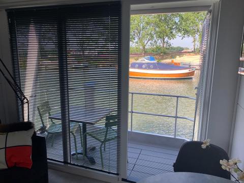 Vista desde la casa flotante Harbour Lodge Amsterdam en Marina Parcs Amsterdam con barco y agua de fondo.
