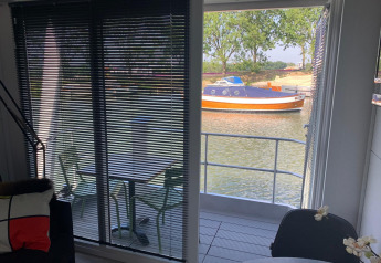 Vista desde la casa flotante Harbour Lodge Amsterdam en Marina Parcs Amsterdam con barco y agua de fondo.