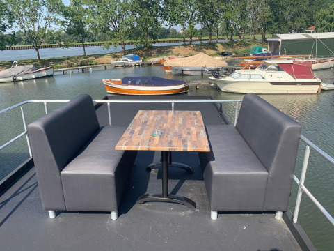 Buiten zitruimte met tafel en banken op een woonboot in Marina Parcs Amsterdam, Nederland.