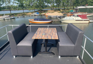 Buiten zitruimte met tafel en banken op een woonboot in Marina Parcs Amsterdam, Nederland.