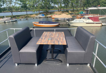 Udendørs siddeområde med bord og to bænke på en husbåd i Marina Parcs Amsterdam, Holland.