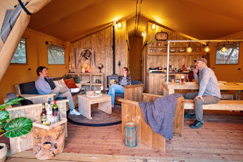 Cuatro personas se relajan en una cómoda tienda safari con muebles rústicos en Marina Parcs Almere, Holanda.