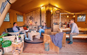 Cuatro personas se relajan en una cómoda tienda safari con muebles rústicos en Marina Parcs Almere, Holanda.