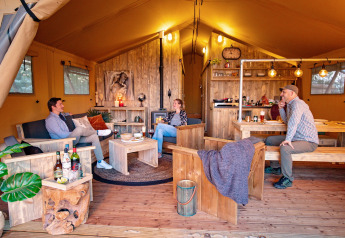 Cuatro personas se relajan en una cómoda tienda safari con muebles rústicos en Marina Parcs Almere, Holanda.