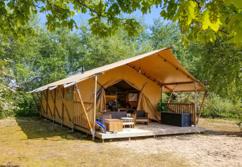 Tente Safari lodge XL à Marina Parcs Almere aux Pays-Bas, entourée d'arbres verdoyants et de nature.