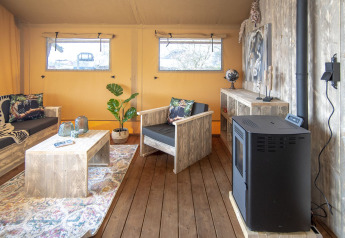 Vue intérieure de la tente Safari lodge XL à Marina Parcs Almere, avec meubles rustiques et décoration bois.