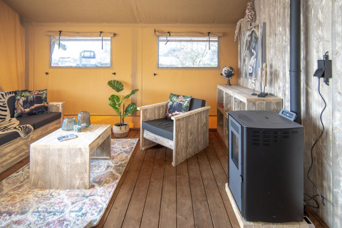 Binnenzicht van Safari lodge XL tent bij Marina Parcs Almere, met rustieke houten meubels en decoratie.