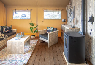 Binnenzicht van Safari lodge XL tent bij Marina Parcs Almere, met rustieke houten meubels en decoratie.