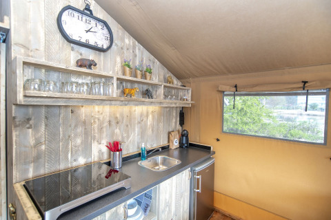 Intérieur du Safari lodge XL à Marina Parcs Almere, Pays-Bas, avec kitchenette et étagères visibles.