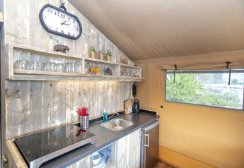 Intérieur du Safari lodge XL à Marina Parcs Almere, Pays-Bas, avec kitchenette et étagères visibles.