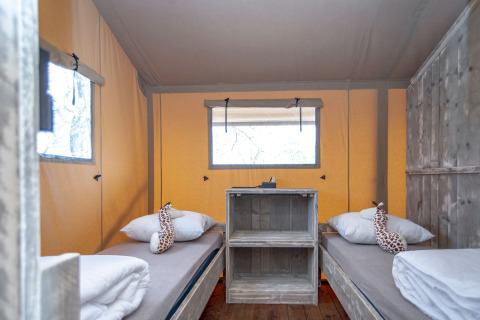 Binnenkant van Safari lodge XL in Marina Parcs Almere met een houten kast en giraffe knuffels op de bedden.