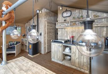 Intérieur d'une tente Safari Lodge XL à Marina Parcs Almere, Pays-Bas, avec cuisine rustique en bois.