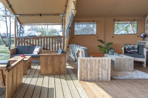 Grande tente safari lodge avec mobilier en bois et coin salon confortable à Marina Parcs Almere, Pays-Bas.