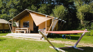 Villatent Outback lodge bij Camping Au Clos de La Chaume in Frankrijk met hangmat en zonnig grasveld.