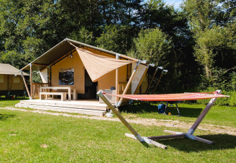 Villatent Outback lodge op Camping Au Clos de La Chaume in Frankrijk met hangmat en groene zonrijke grasmat.