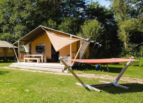 Lodge Villatent Outback en Camping Au Clos de La Chaume en Francia, con hamaca y entorno verde soleado.