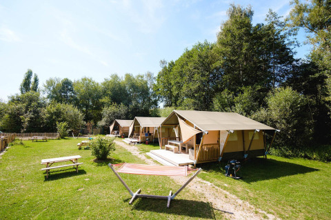 Villatent Outback lodge al Camping Au Clos de La Chaume in Francia, con tende, tavoli da picnic e amaca.
