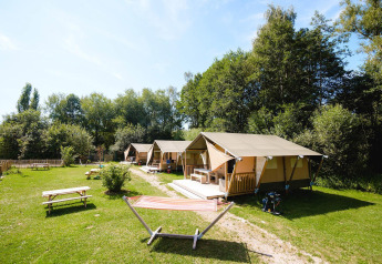 Villatent Outback lodge bij Camping Au Clos de La Chaume in Frankrijk, met tenten, picknicktafels en hangmat.