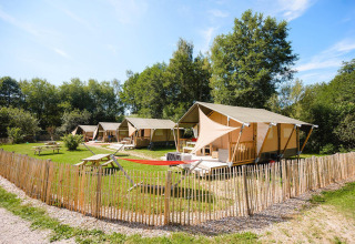 Lodges Villatent Outback en Camping Au Clos de La Chaume, Francia, rodeados de naturaleza y césped verde.