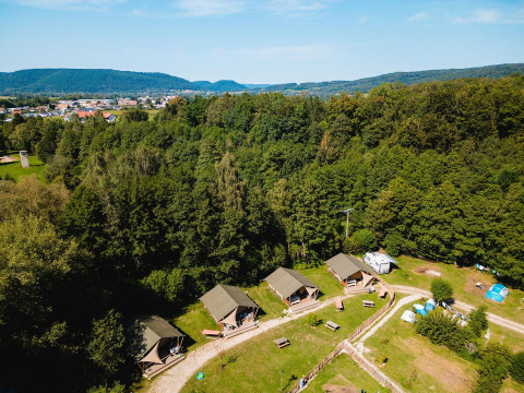 Luftfoto af Villatent Outback ved Camping Au Clos de La Chaume i Frankrig, omgivet af skov og grønne områder.