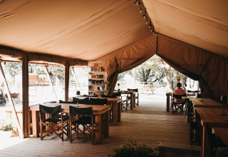 Interno di una tenda comune con tavoli e sedie in legno al Camping Luna del Monte in Umbria, Italia.