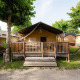 Tenda safari 'Villatent Outback' con veranda in legno al Campeggio del Garda in Italia, circondata da alberi.