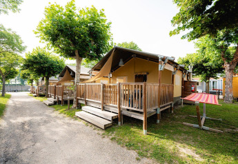 Safaritent Villatent Outback op Campeggio del Garda in Italië met houten terras en groene bomen.
