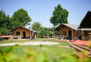 Tentes safari Villatent Nomad au Camping Betuwestrand aux Pays-Bas, entourées de verdure et d’arbres.