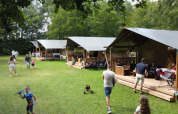 Familier nyder udendørsaktiviteter foran telt-hytter på Camping de Beukenhof, feriepark i Drenthe, Holland.