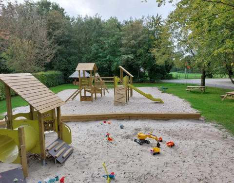 Parque infantil con cajón de arena y juegos de madera en Camping de Beukenhof, Drenthe, Países Bajos.