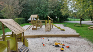 Parque infantil con cajón de arena y juegos de madera en Camping de Beukenhof, Drenthe, Países Bajos.